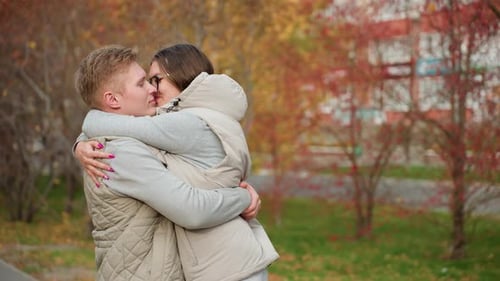 Couple Embrace Affectionately Sharing Warm Kiss in Scenic Autumn Park Setting