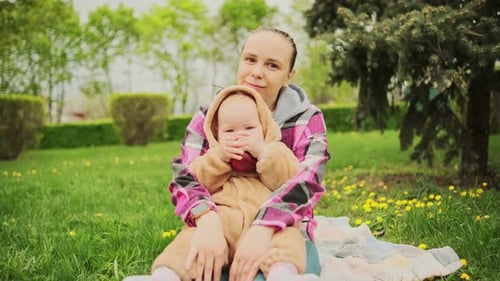 A Mother and Her Baby Enjoy a Beautiful Spring Day in the Park They are Sitting on a Blanket