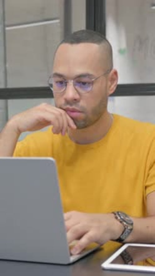 Young Adult Uses Laptop While Thinking in Office