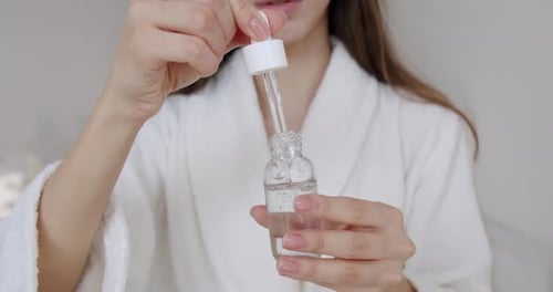 Woman Drawing Serum into Dropper from Bottle