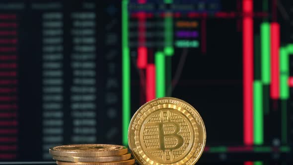 Close view of multiple physical Bitcoins with moving digital charts ...