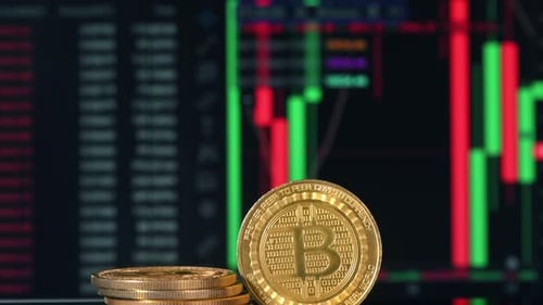 Close view of multiple physical Bitcoins with moving digital charts