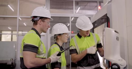 male and female engineers cooperate in slowmotion during robotic arm positioning session inside