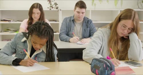 Students Learning in School Class Room. High School or College Aged Young Adults Studying & Writing