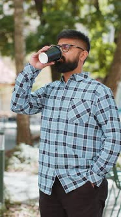 Happy Indian Man Enjoying Drinking Morning Coffee Hot Drink Relaxing Taking a Break on City Street