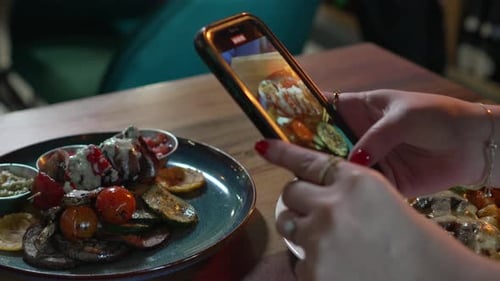 Hands of a woman photographing appetizing food with her smartphone