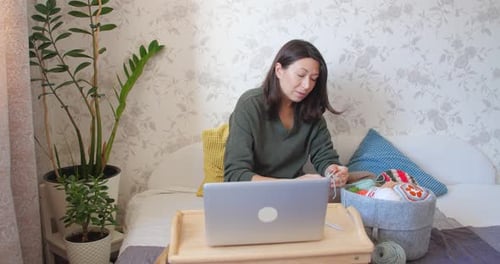 Woman on Video Call Knitting on Bed