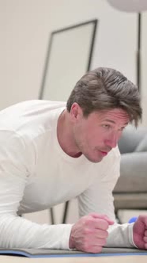 Man Works Out Doing Plank Exercise on Mat