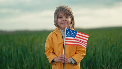 Boy Holding American Flag in a Grassy Field