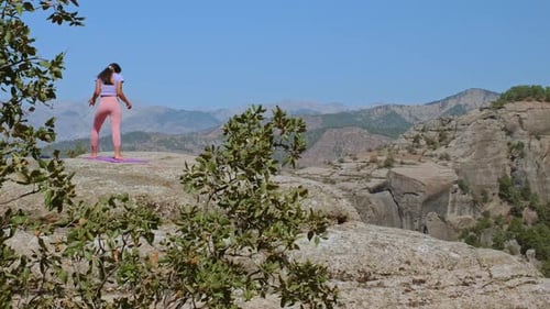 Woman Practicing Yoga Balance Pose on Cliff with Mountain View
