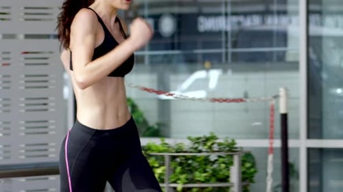 4k video footage of a young woman jogging through the city alone