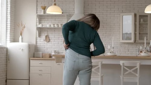 Rear View of Overweight African American Woman Trying to Fit Into Tight Jeans