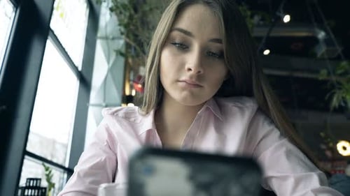 Young, Pretty Girl Staring at Smartphone in Cafe 20s