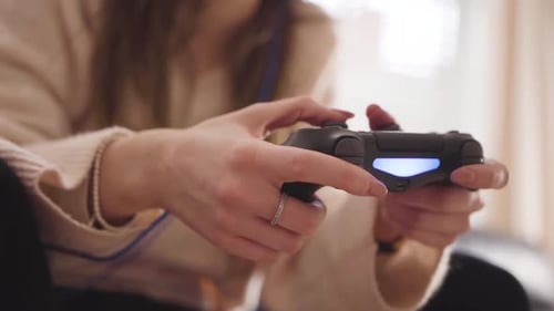 Girl playing a computer game on the sofa at home (SLOW MOTION) Close-up of controller