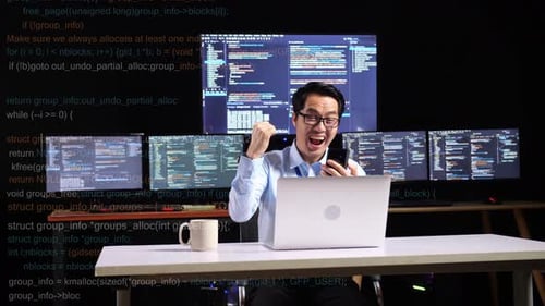 Man Cheers While Looking at Phone at Desk
