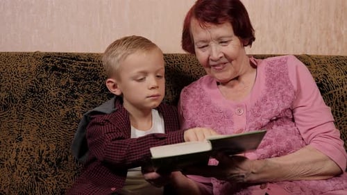 Grandmother Reading Book with Grandson on Couch