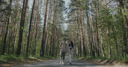 Slow Motion of Cheerful Man and Woman Walking in Green Park Holding Hands and Talking Enjoying
