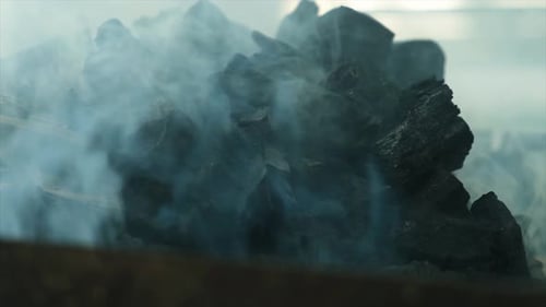 A Heap of Black Lump Charcoal Pieces for Barbecue Releasing Thick Acrid Smoke During Ignition Dense