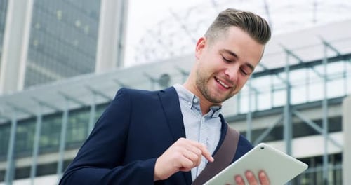 4k video footage of a young businessman using a digital tablet in the city