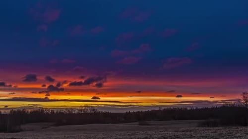 Timelapse of clouds moving in colorful sky with rising sun at horizon over snowy landscape at sunris