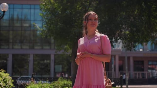 Woman Near Glass Building Girl in Rosy Attire Enjoys Serene Park Surroundings Young Woman Dressed in