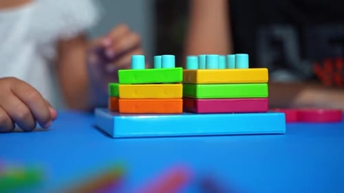 Child Plays With Colorful Toy at a Blue Table
