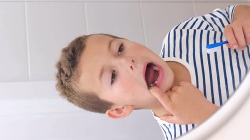 Boy Brushing Teeth in Bathroom Mirror Close-Up