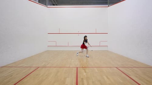 Lady Squash Player Strikes Ball Against Side Walls on Court