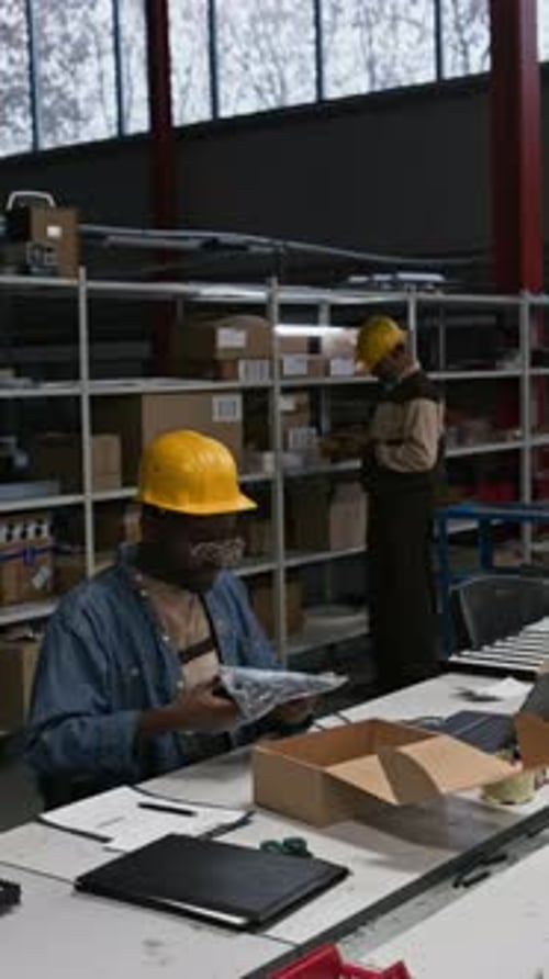Schwarzer männlicher Industriefabrikleiter verpackt Produktprobe in Schachtel