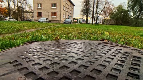 Stadtsilhouette und Kanaldeckel an einem bewölkten Tag