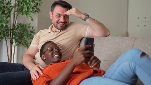 Couple Relaxing on Sofa While Using Phone