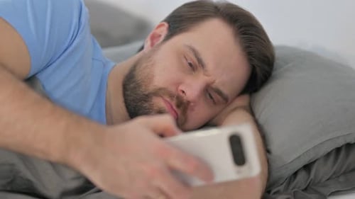 Man Resting in Bed with Smartphone