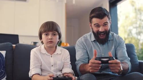 Father and son play video games on couch