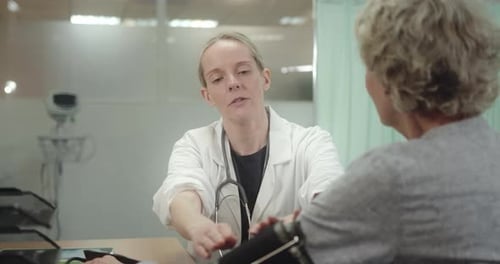 Doctor taking Senior Patient Blood pressure in Doctors Office