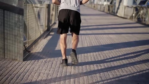 Rear View of an Unrecognizable Sport Mature Man Running Outdoors in the Morning Through a Bridge
