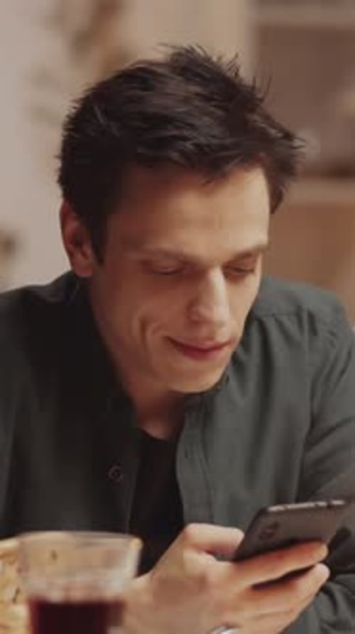 Young Adult Using Phone While Sitting at Table