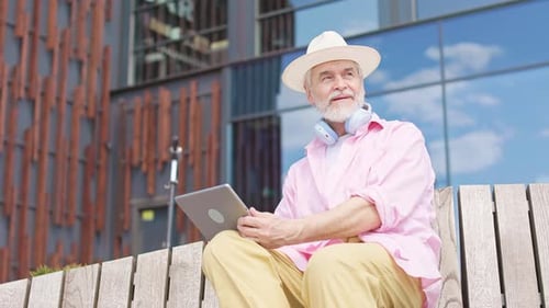 Older Man Engrossing in Tablet While Sitting on Wooden Bench
