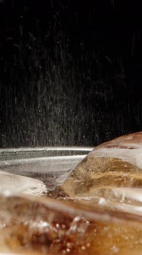 Ich gieße Cola in ein Glas mit Eis, Seifenblasen und Spritzern. Dolly Slider in extremer Nahaufnahme. Laowa-Sonde