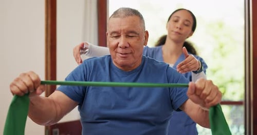 Man Exercising with Therapy Band Assisted by Healthcare Worker