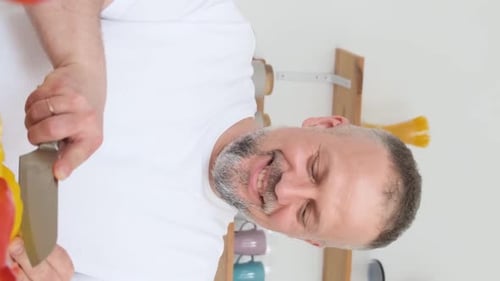 Smiling Man Slicing Bell Peppers in the Kitchen