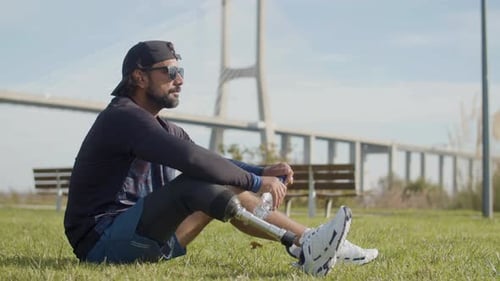 Athlete with Prosthetic Leg Drinks Water Outdoors