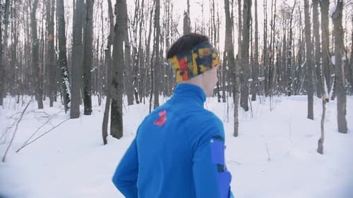 Young Man and Woman Running in Winter Forest at Early