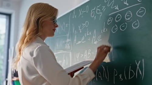 Woman Writes Math Equations on Chalkboard in Classroom