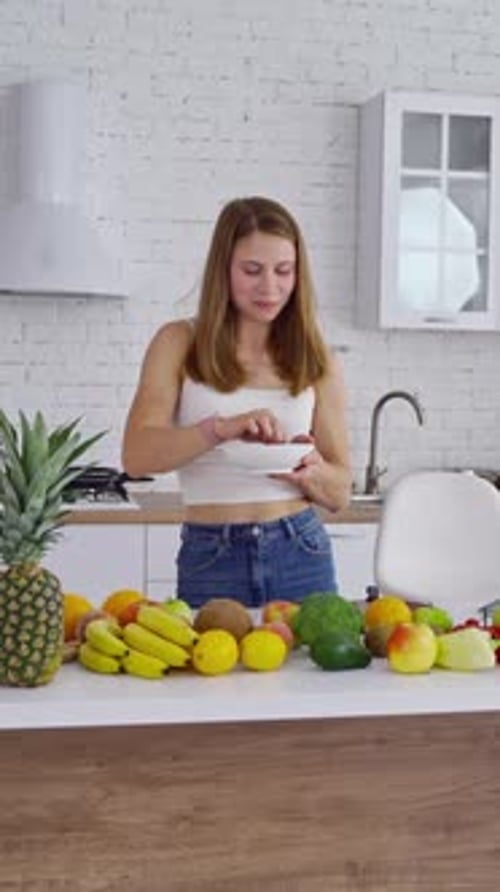Young Adult Woman Eating from Bowl in Kitchen