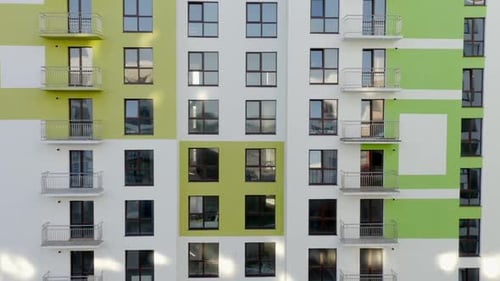 Tilt Up View of Contemporary Apartment Building with Large Windows and Colorful Walls of the Facade