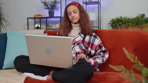 Girl Using Laptop Computer Sitting on a Sofa