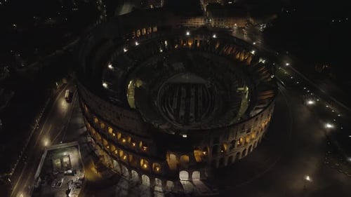 Aerial view around the illuminated Colosseum, in Rome, Italy - high angle, orbit, drone shot