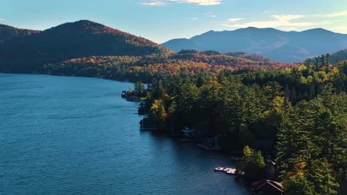 Lake placid New York shimmers below mountains as drone captures summer paddling