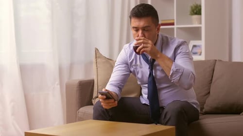 Upset Man with Smartphone and Glass of Wine
