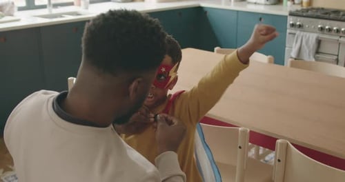 Dad helps child put on superhero costume